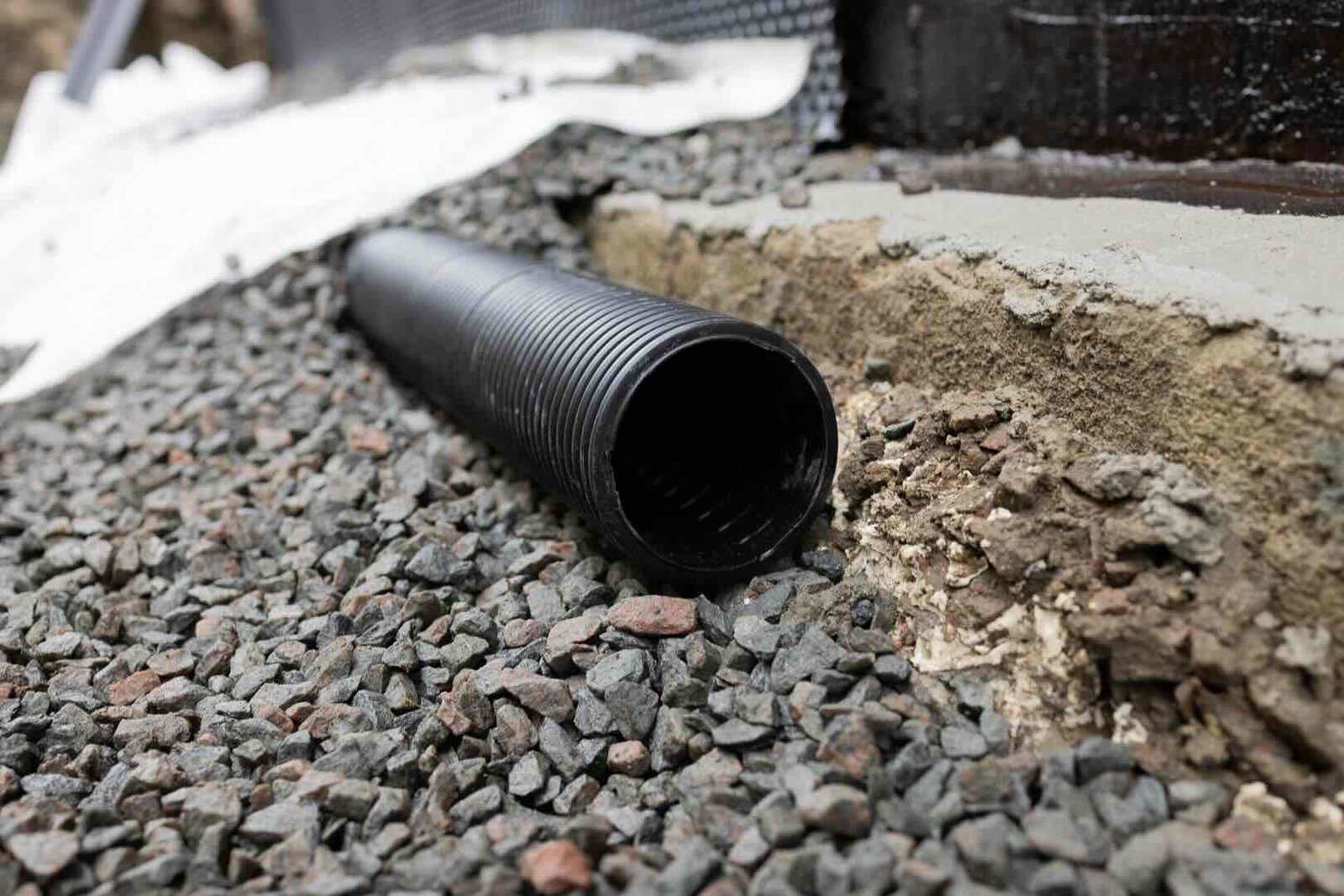 dranering En bild där husgrunden har grävts upp och en ny dränering installeras.